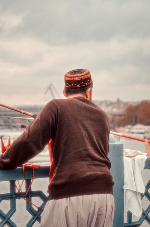 A man in a hat looking out over the water