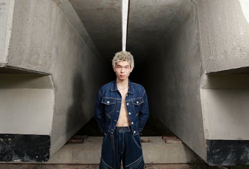 A man in denim jacket and shorts standing in an underground tunnel