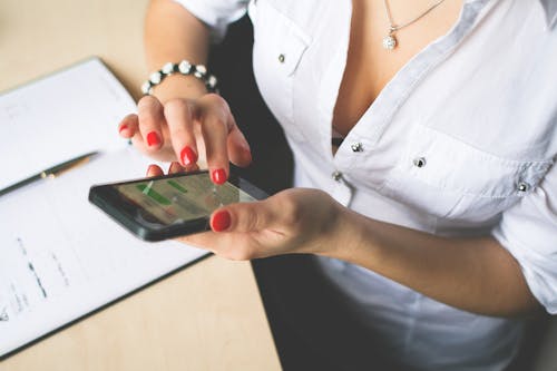 Free Woman in White Button Up Top and Holding Black Android Smartphone Stock Photo
