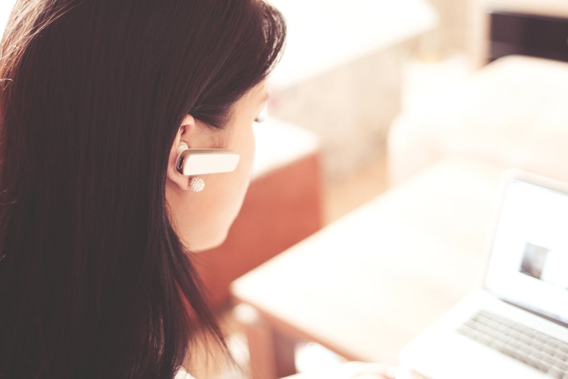 Auricolare Da Portare Della Donna Che Utilizza Computer Portatile Bianco