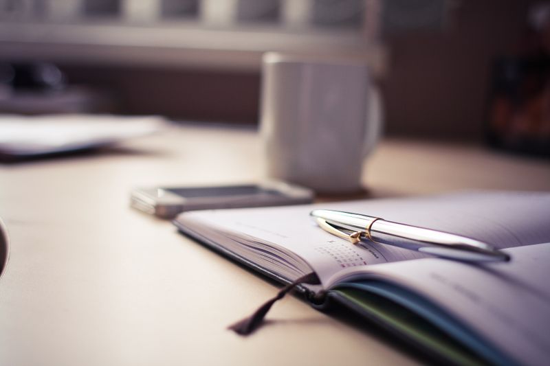laptop open at a desk with a coffee mug and a clock in frame