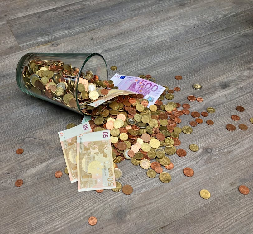 бесплатная Монеты и банкноты, разбросанные на серой деревянной поверхности Стоковое фото