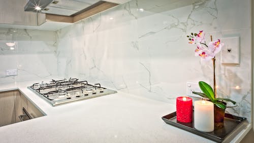 Kostenlos Zwei Hellrote Und Weiße Stumpenkerzen Neben Rosa Orchideenblumen In Der Küche Stock-Foto