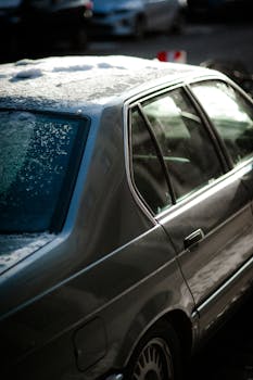 A classic car parked in Berlin during winter, with snow on its roof.