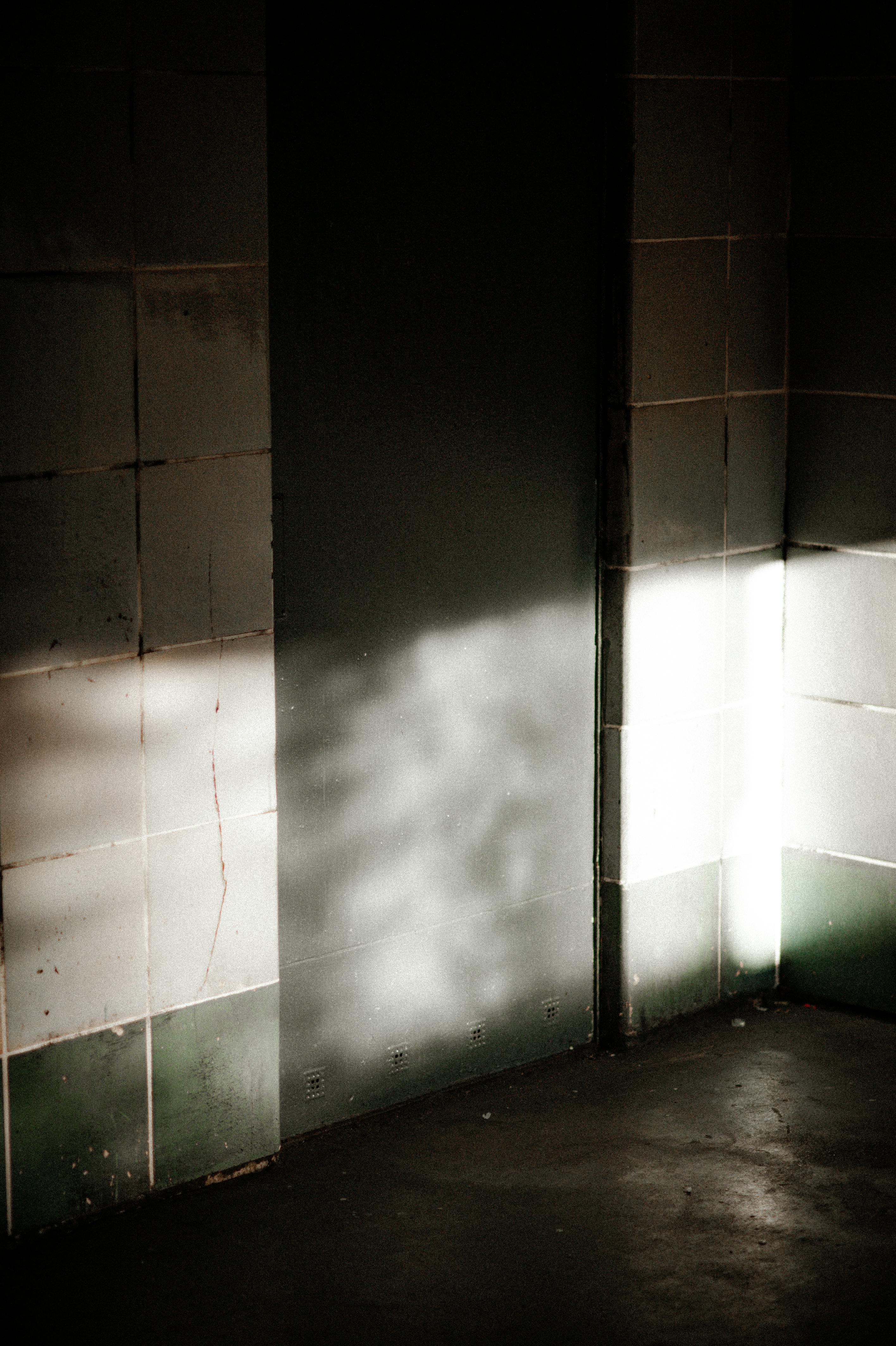 Free Sunlight casts intriguing shadows on a tiled wall in an industrial building in Berlin, Germany. Stock Photo