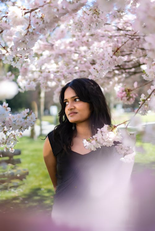A woman standing in front of a tree with pink blossoms