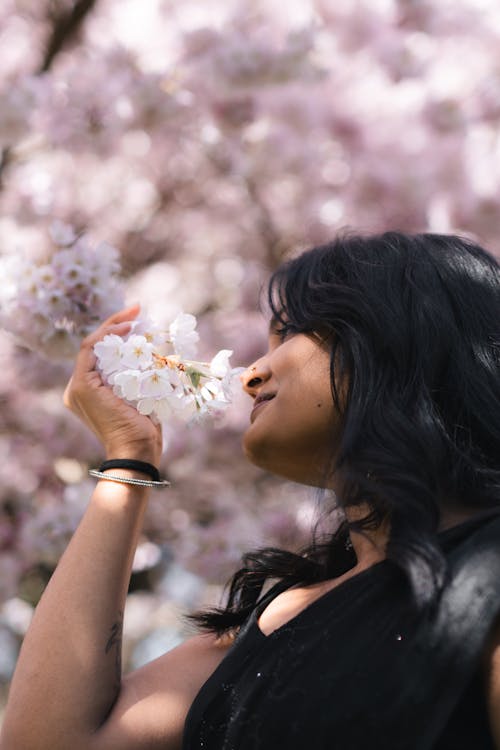 A woman smelling the flowers on a tree