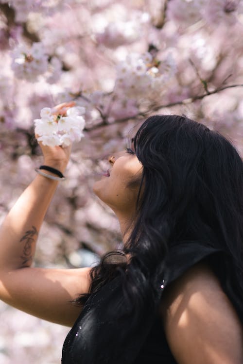 A woman smelling a cherry blossom tree