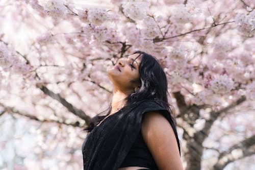 A woman in black standing under a cherry blossom tree