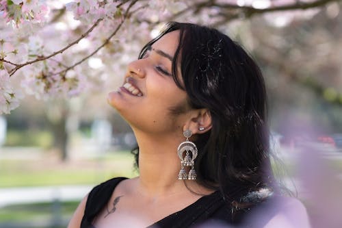 Free A woman smiling while looking at the cherry blossom tree Stock Photo