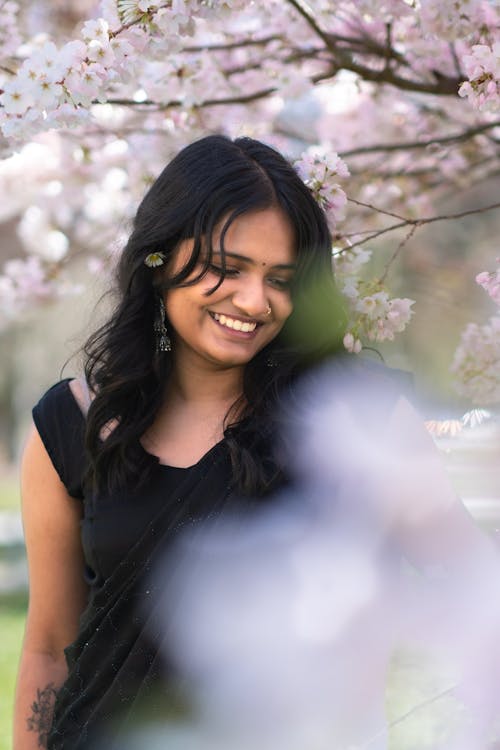 A woman smiles while standing under a tree