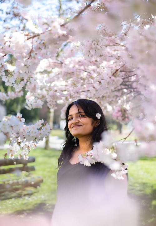 A woman standing under a tree with pink blossoms