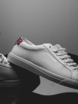 Close-up of elegant white sneakers with perforated texture and pink accent.