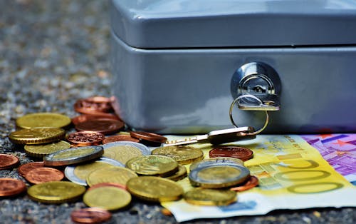 Банкноты и монеты рядом с серым сейфом