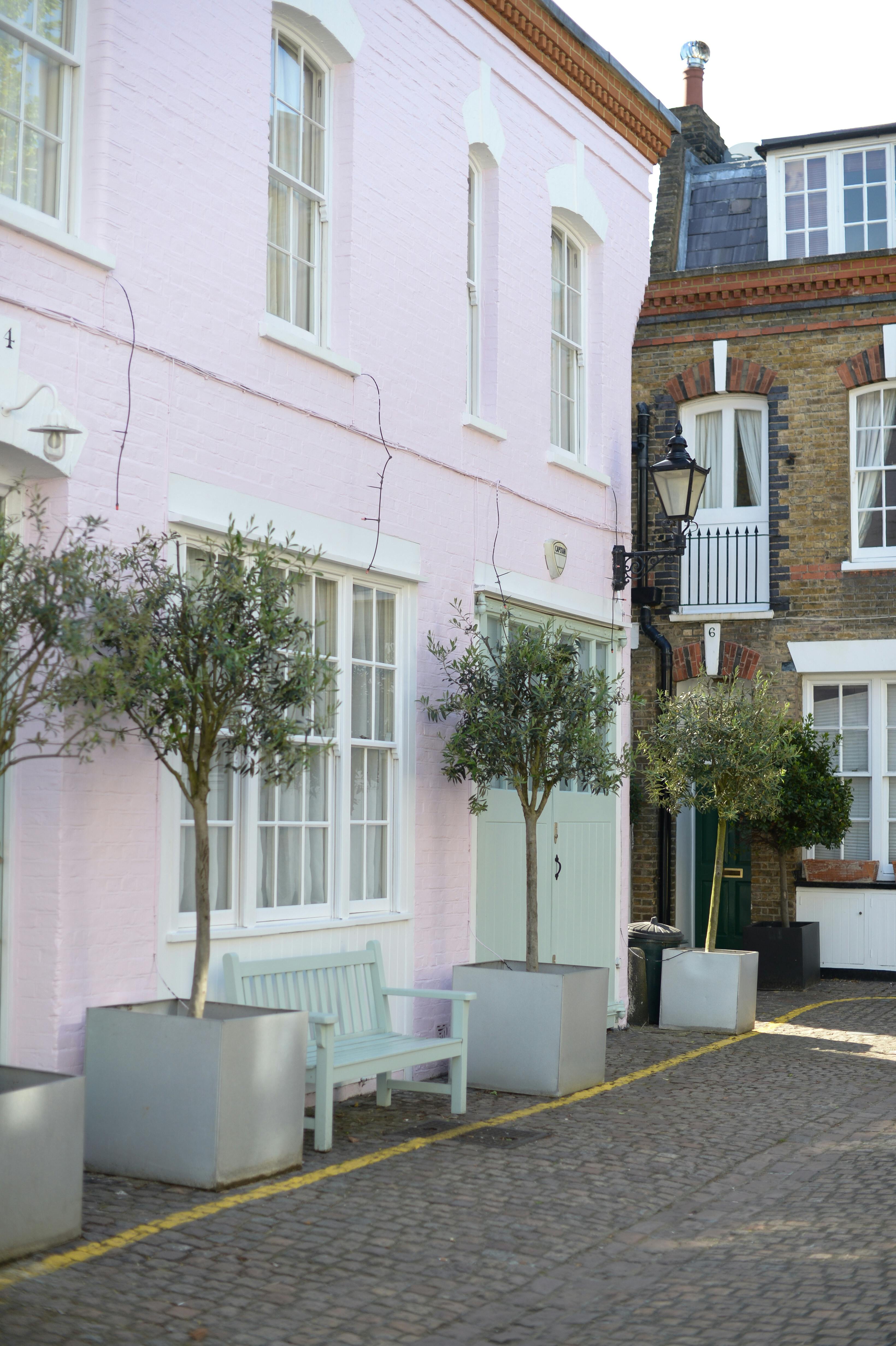 Idyllic courtyard featuring a pastel pink building, trees, and bench, perfect for peaceful urban living.