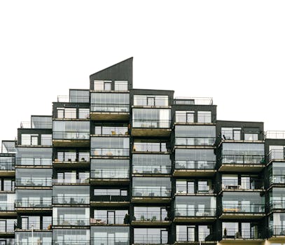Contemporary apartment building with geometric facade and glass balconies, showcasing modern architecture.