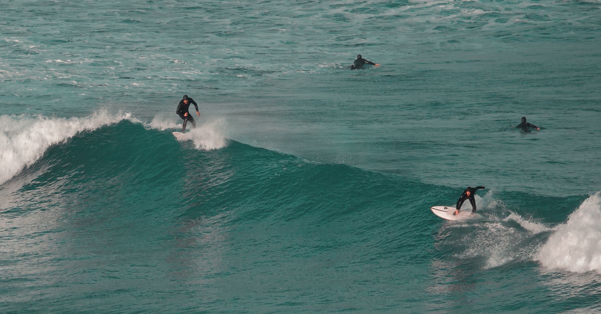Surfer riding a wave at sunset — best budget surf cities 2026
