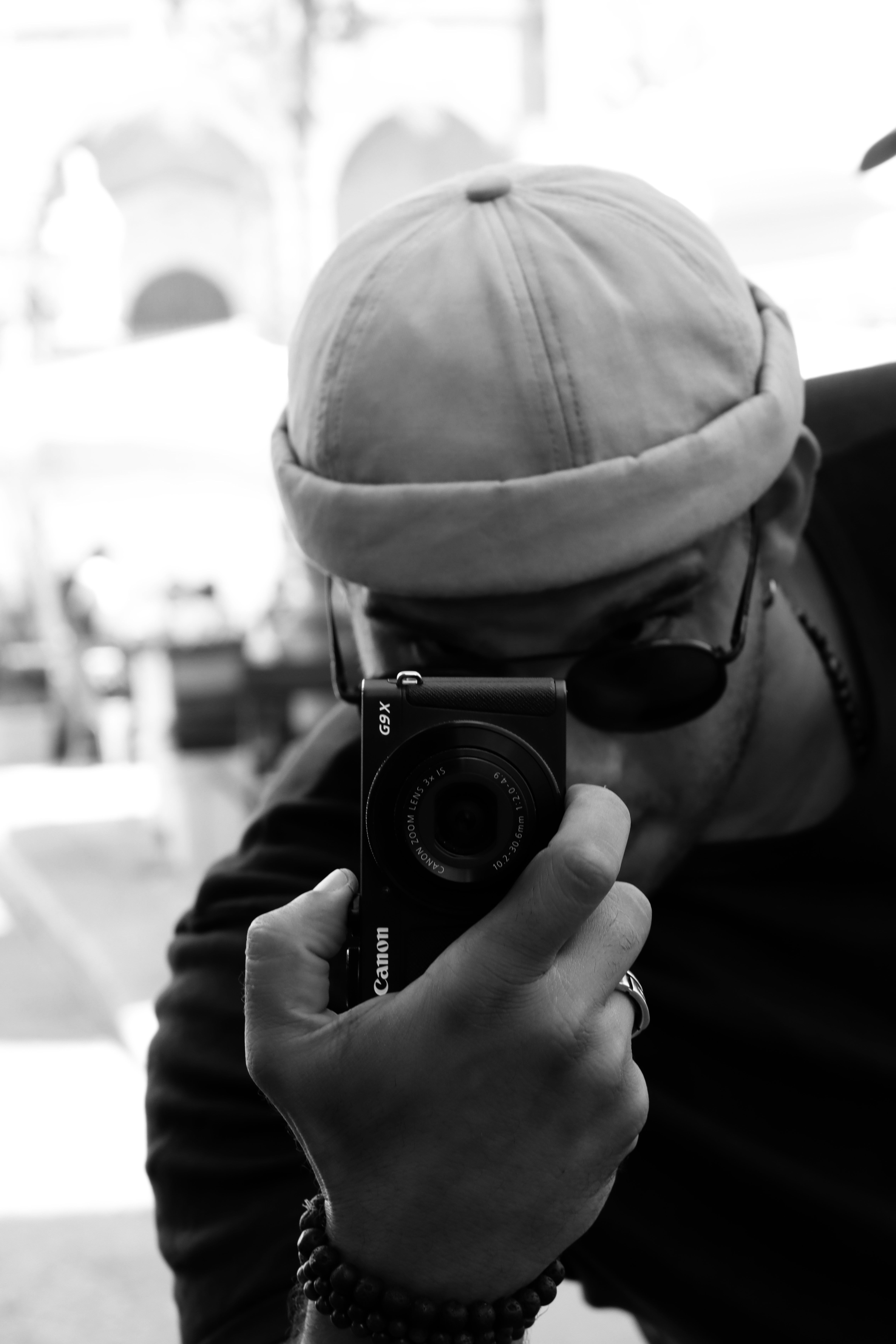 Black and white portrait capturing a man photographing with a camera in Cefalù, Sicily.