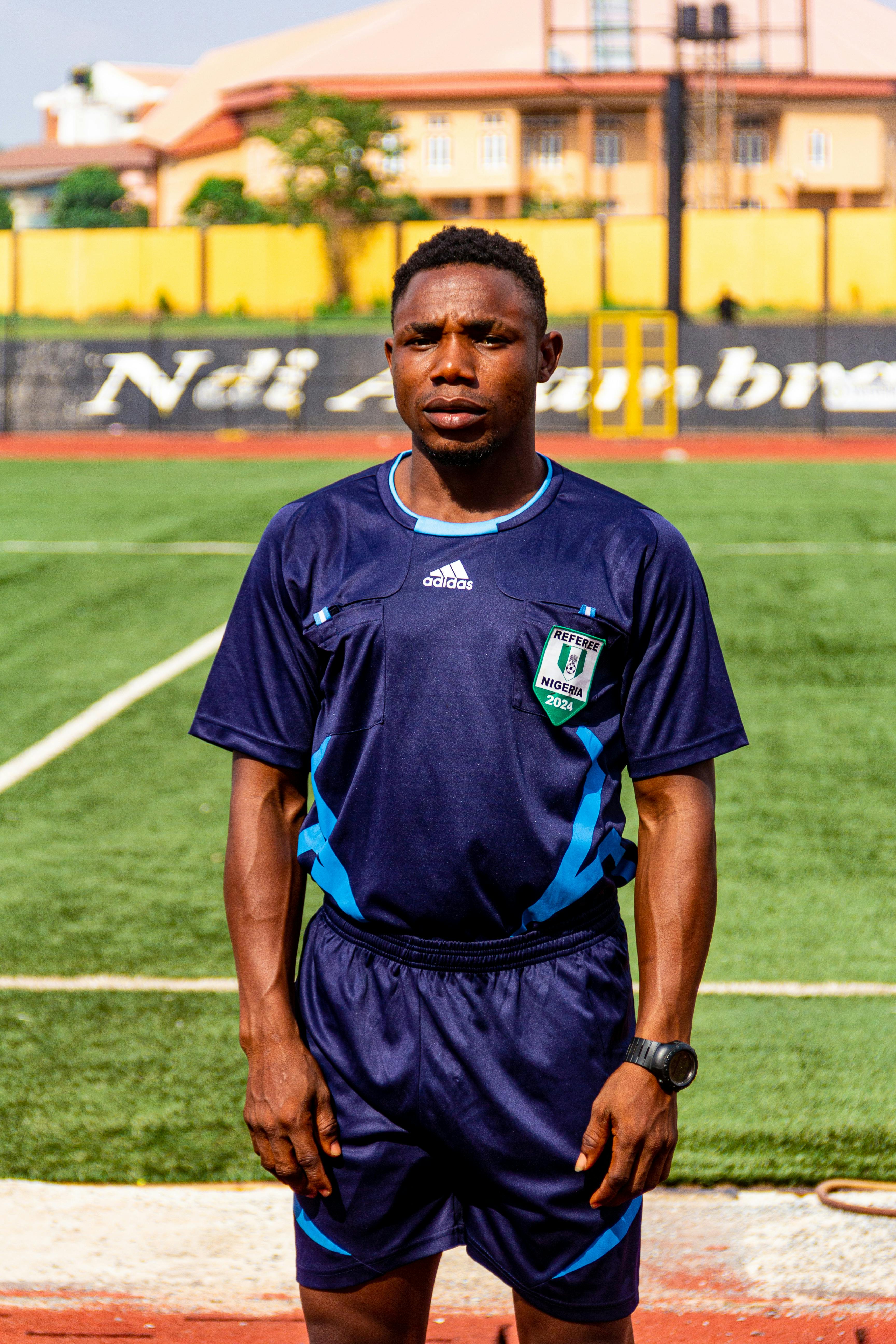 A soccer player stands on a green field wearing blue sportswear, ready to play.