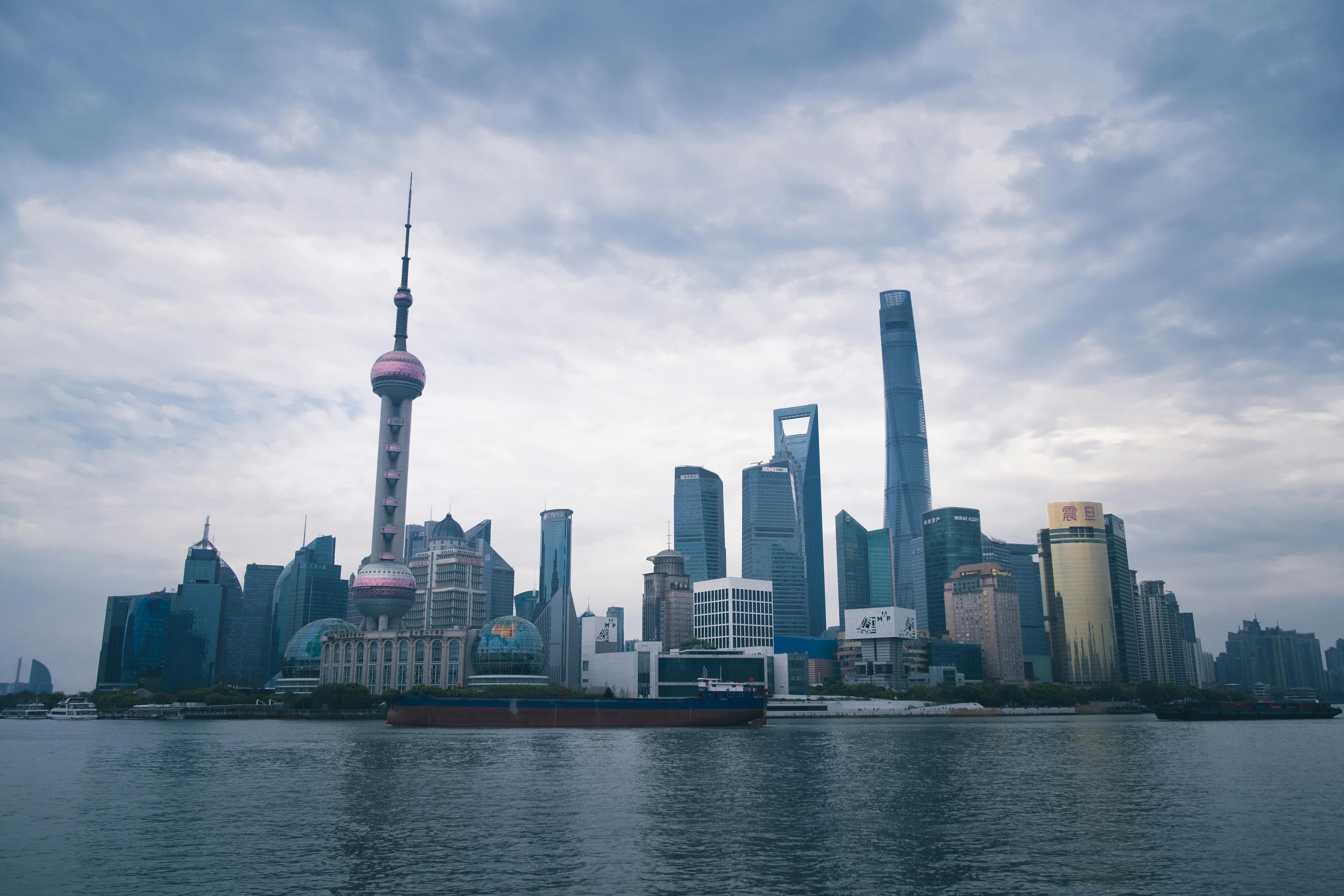 Panoramic view of Shanghai skyline with iconic Oriental Pearl Tower under cloudy sky.