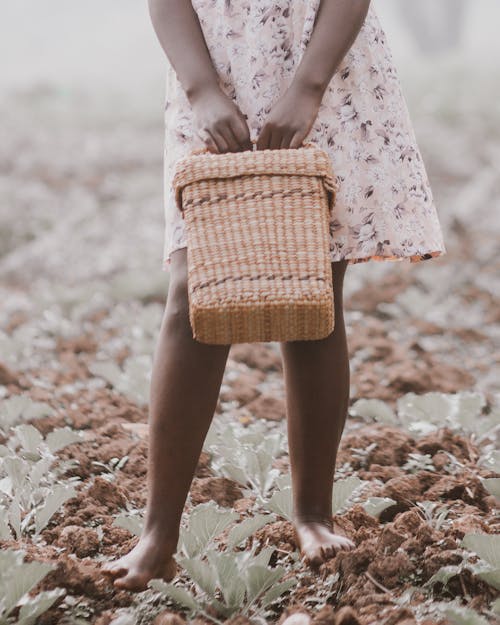 A young girl holding a basket in the middle of a field