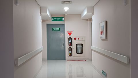Quiet hospital corridor leading to emergency exit, features clean and minimal design.