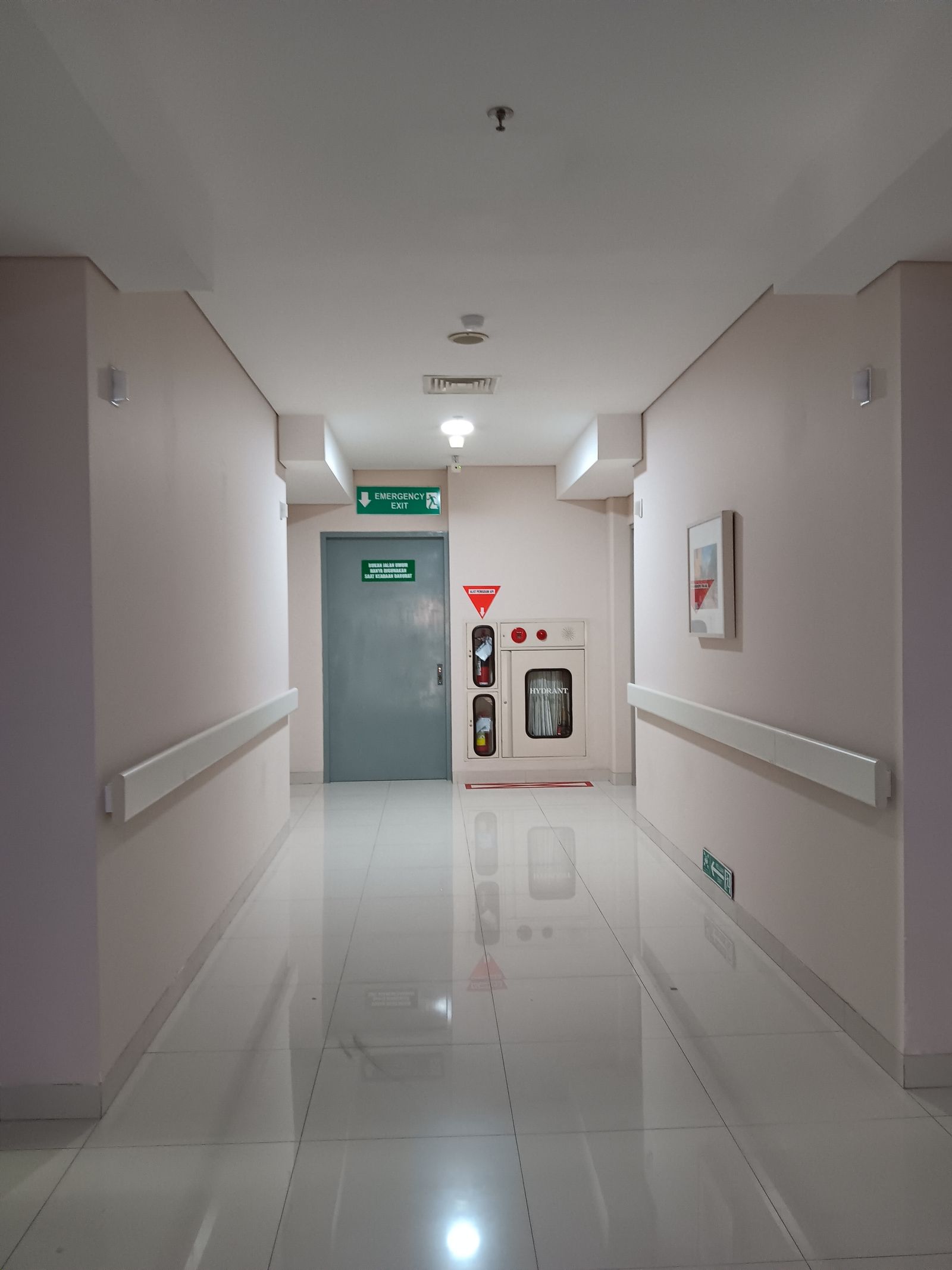 Couloir de maison de santé en fin de journée, chariot de bio-nettoyage à l'entrée d'une salle de soins