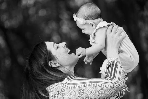Free A happy mother lovingly holds her baby daughter in an outdoor setting, captured in black and white. Stock Photo