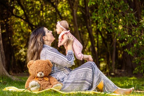 Free A mother joyfully plays with her baby in a lush outdoor setting, creating precious memories. Stock Photo