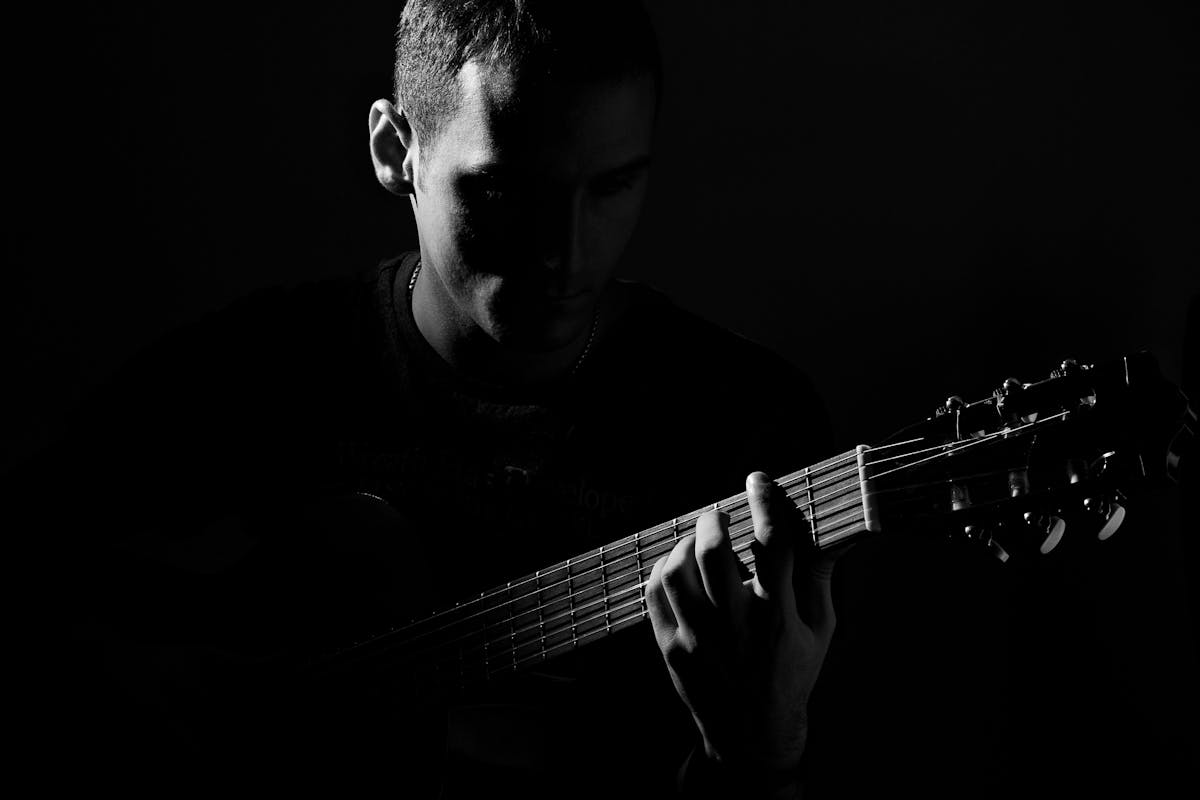 Grayscale Photo of Man Playing Guitar
