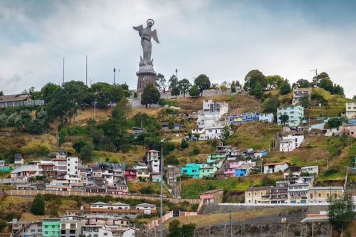 Free Colorful hillside homes beneath the iconic El Panecillo statue in Quito. Stock Photo