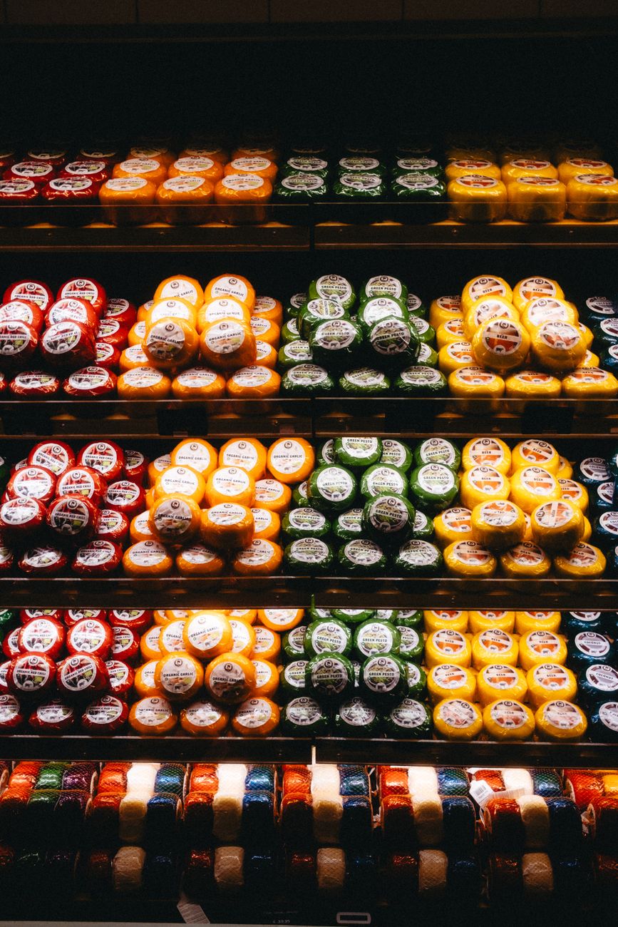 Kleurrijke presentatie van diverse kaassoorten op planken in een winkel in Amsterdam.