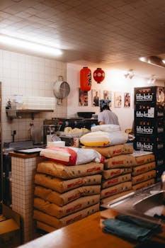 Warmly lit restaurant kitchen in Amsterdam with chef at work, piled with food supplies.