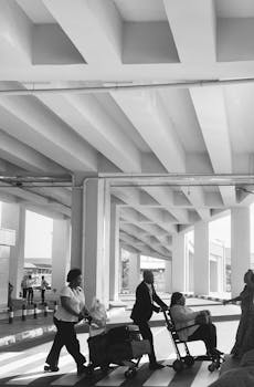 Black and white photo of people crossing at Accra airport with a stark architectural backdrop.