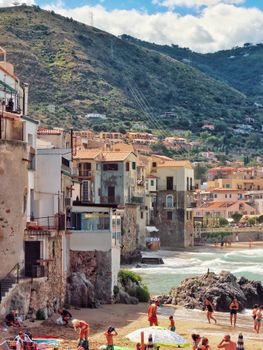 Explore a picturesque coastal town featuring charming buildings, sunny beach, and scenic hillside views.