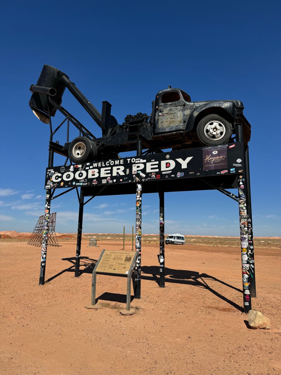 Old road train mounted on a welcome sign above an outback town entrance.