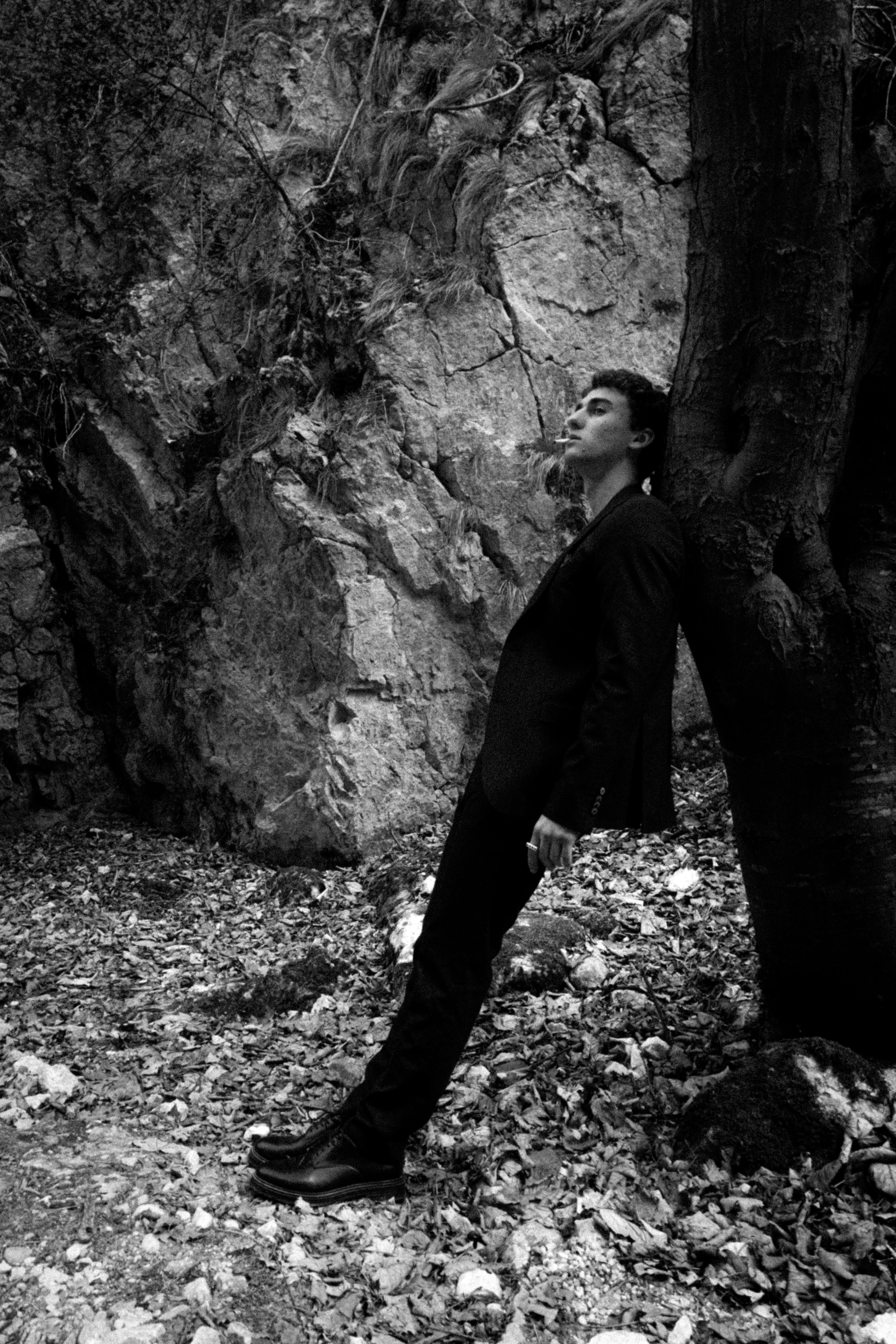 A man in a suit leaning against a tree · Free Stock Photo
