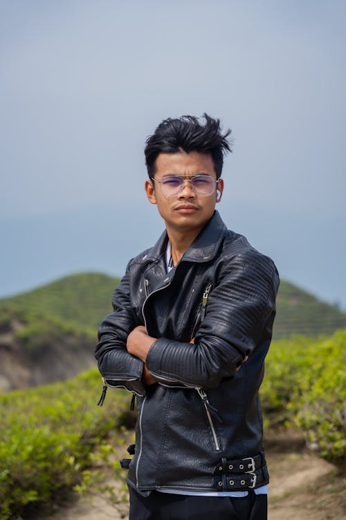 A young man in a leather jacket standing on a hill