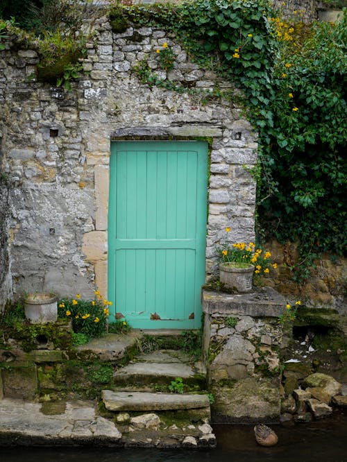 A green door is next to a stone wall