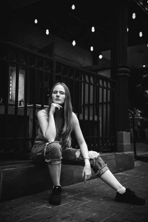 Free Caucasian woman in black and white sitting in a fashionable urban setting, exuding confidence and elegance. Stock Photo