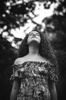 Elegant black and white portrait of a woman in nature with curly hair and a sundress.