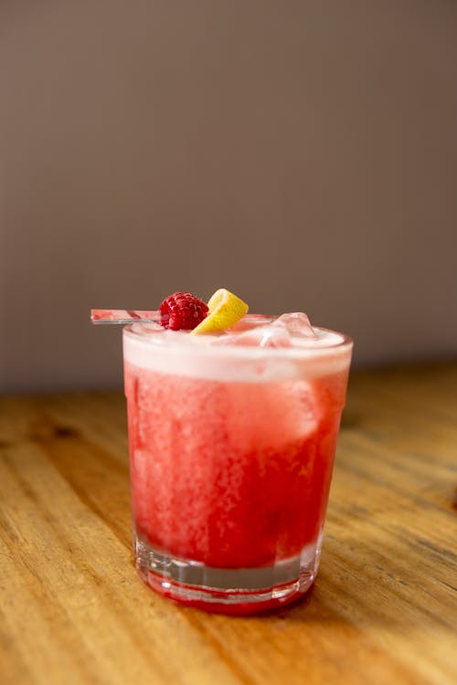 Free A cocktail with a lemon wedge and raspberry garnish Stock Photo