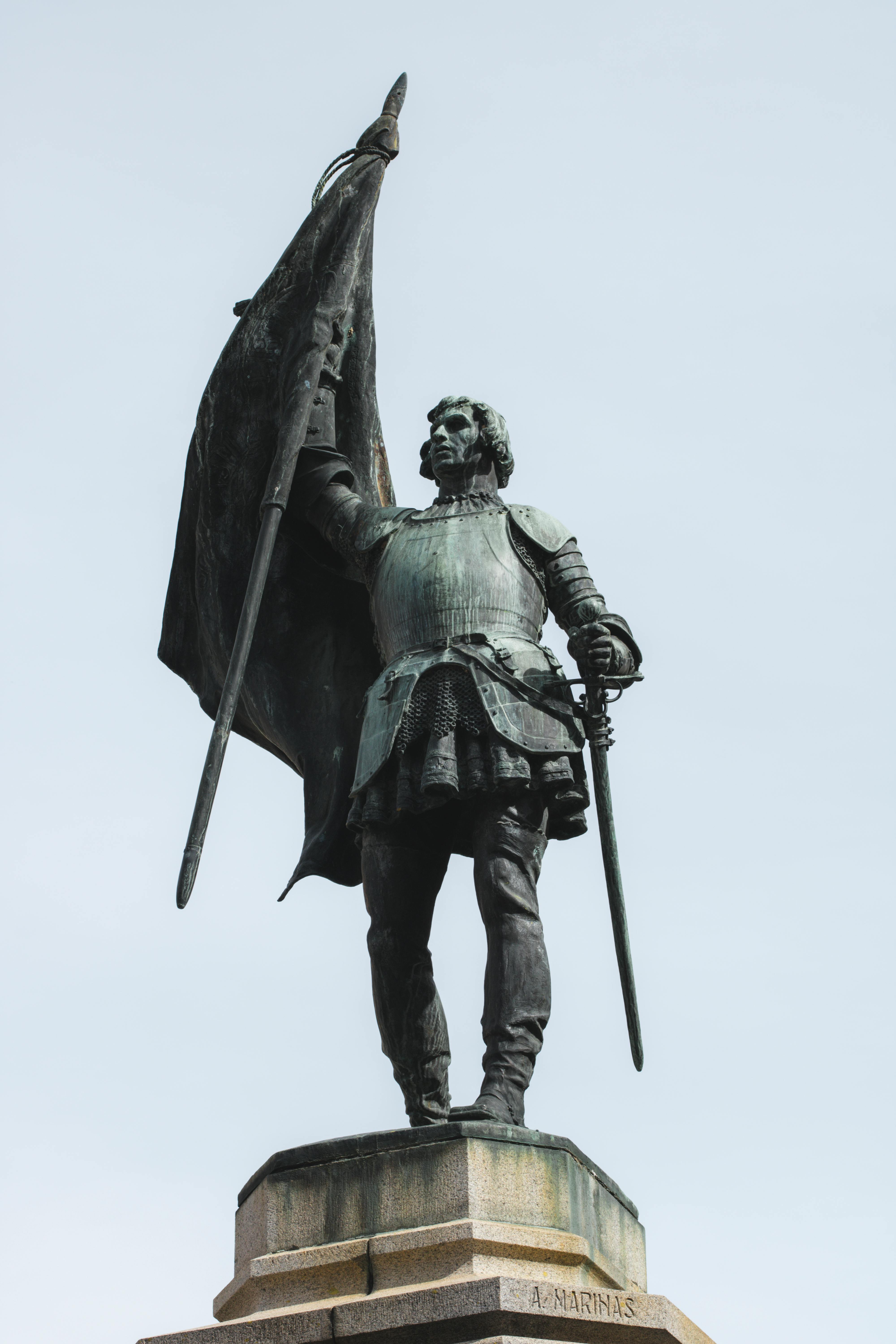 Sculpture of Juan Bravo holding a flag in Segovia, Spain's historic landmark.
