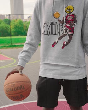 Street style fashion photo featuring a person with basketball wearing a graphic hoodie on an outdoor court in Atlanta.
