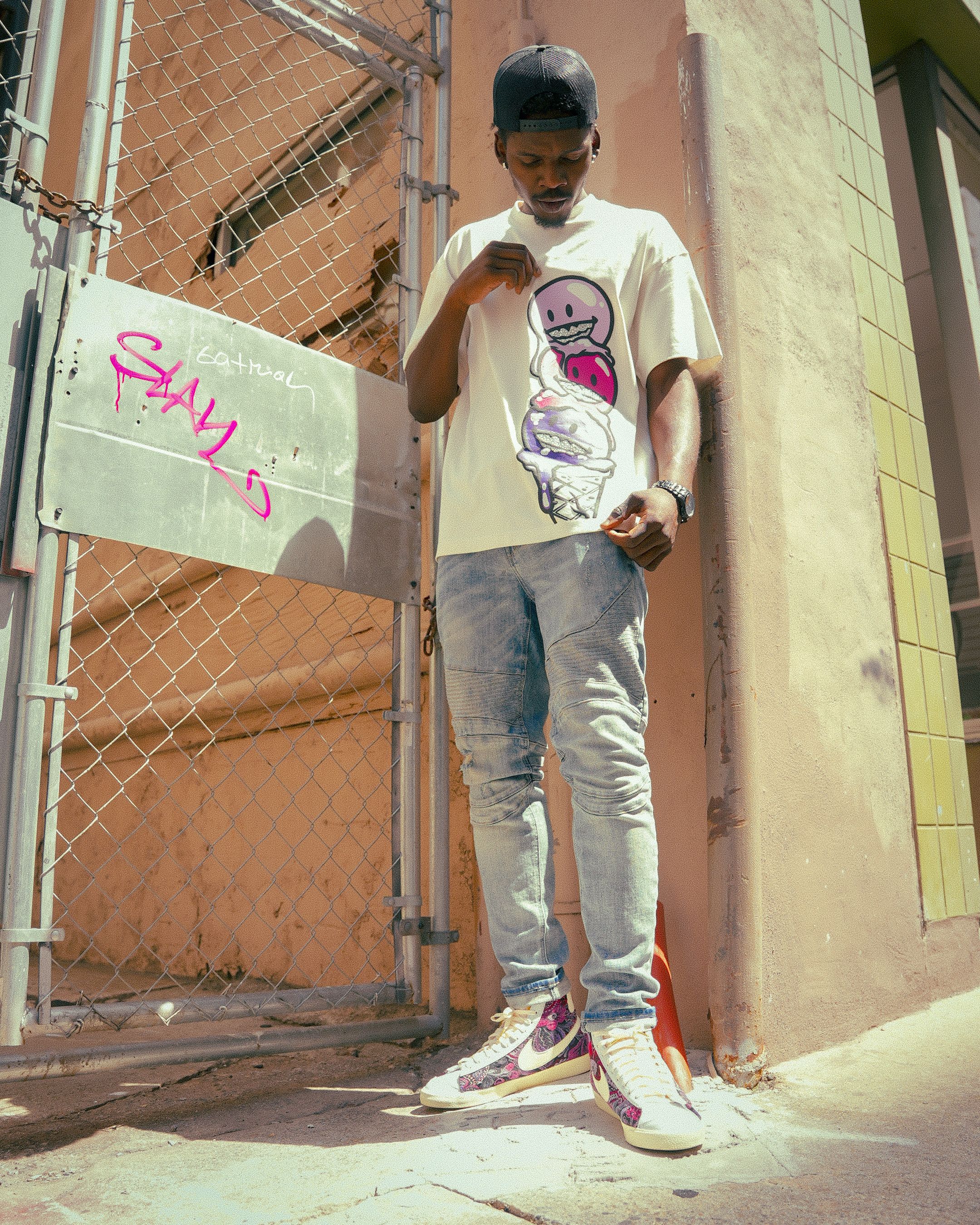 Stylish man poses in Atlanta street with vibrant fashion and urban graffiti backdrop.