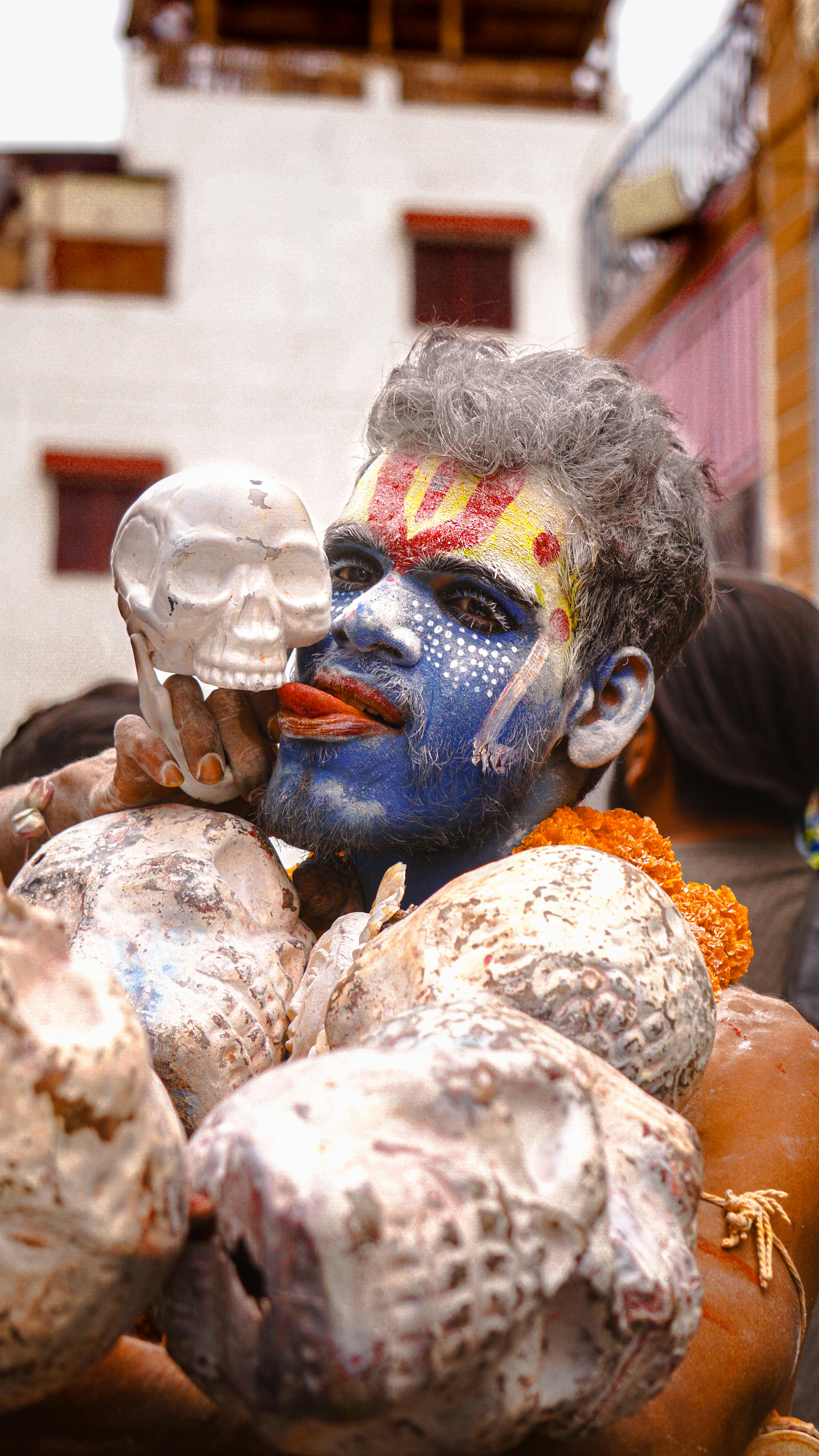 Spiritual Aghori Sadhu in Varanasi adorned with vibrant artistic makeup and skulls for ritualistic practice.