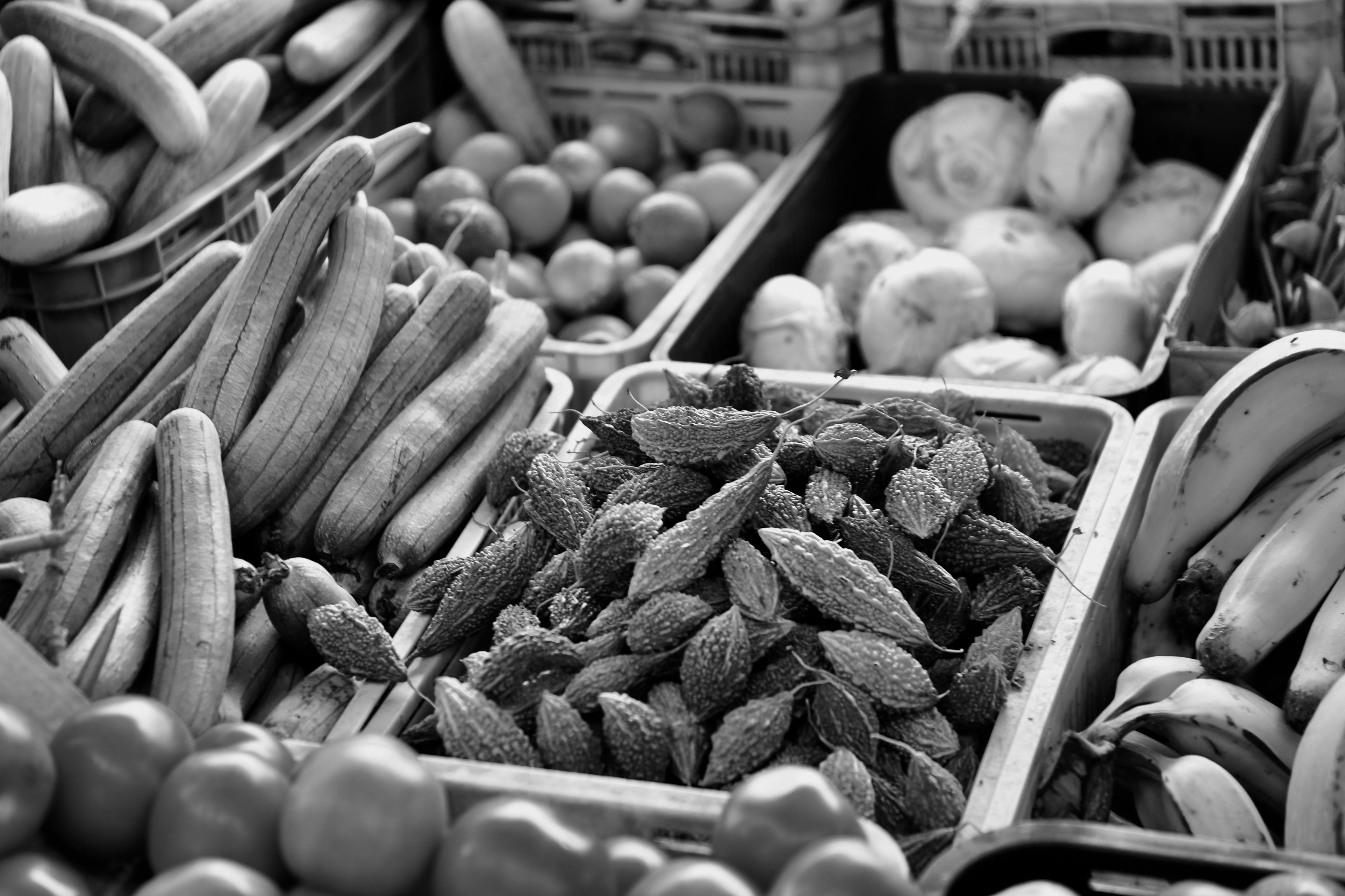 Explore the variety of fresh fruits and vegetables on display at a Singapore market stall, captured in black and white.