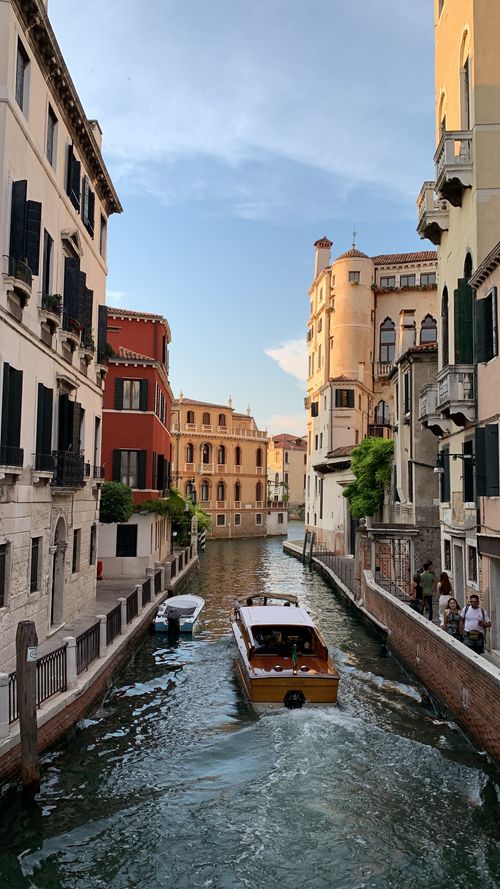 Free Explore a beautiful canal in Venice with historic buildings and a boat under a sunny blue sky. Stock Photo