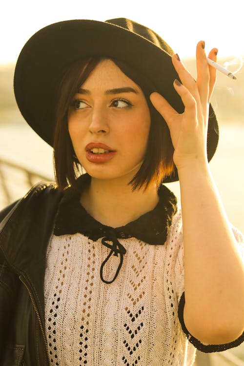 A woman in a hat and jacket smoking