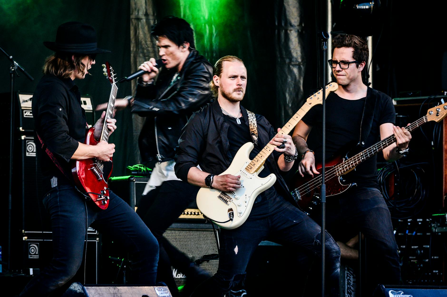 Rock band performing live with guitars and microphone on stage. Energetic and dy
